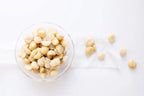Glass bowl filled with flavoured macadamia nuts on a white background