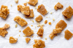 Caramel with macadamia brittles in pieces on a white surface photo from Nutworks