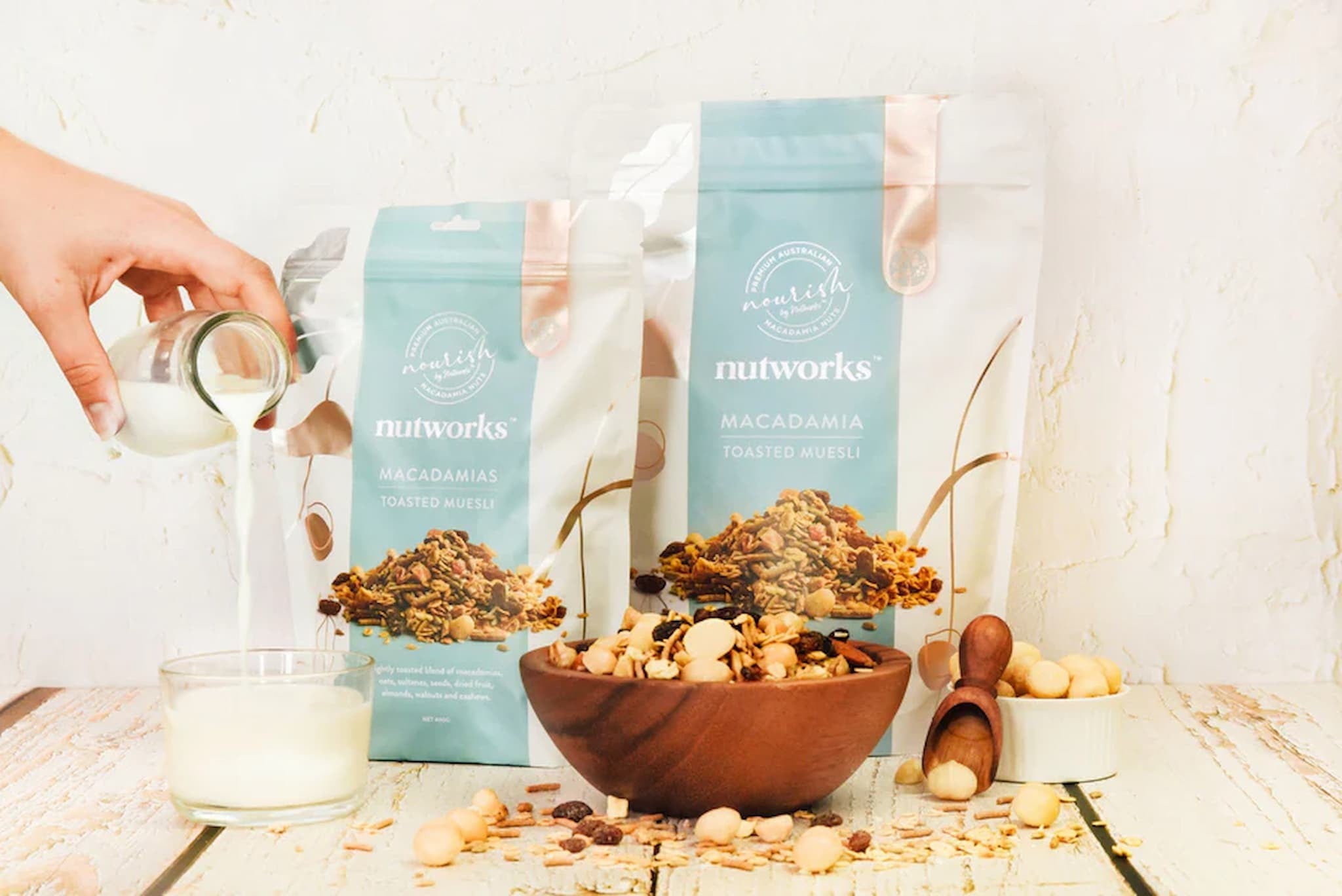 An image showing the different sizes of macadamia toasted muesli with a bowl containing muesli and milk from Nutworks