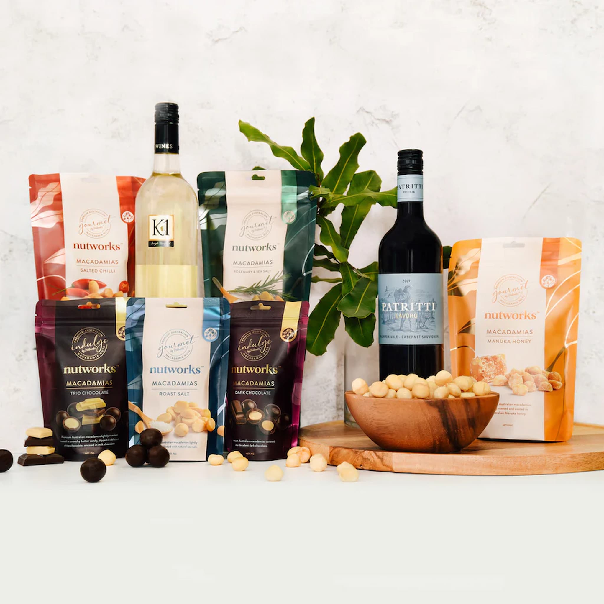 Deluxe hamper of premium Australian macadamia nut packaging and wine bottles on a white surface with a plant in the background photo from Nutworks.