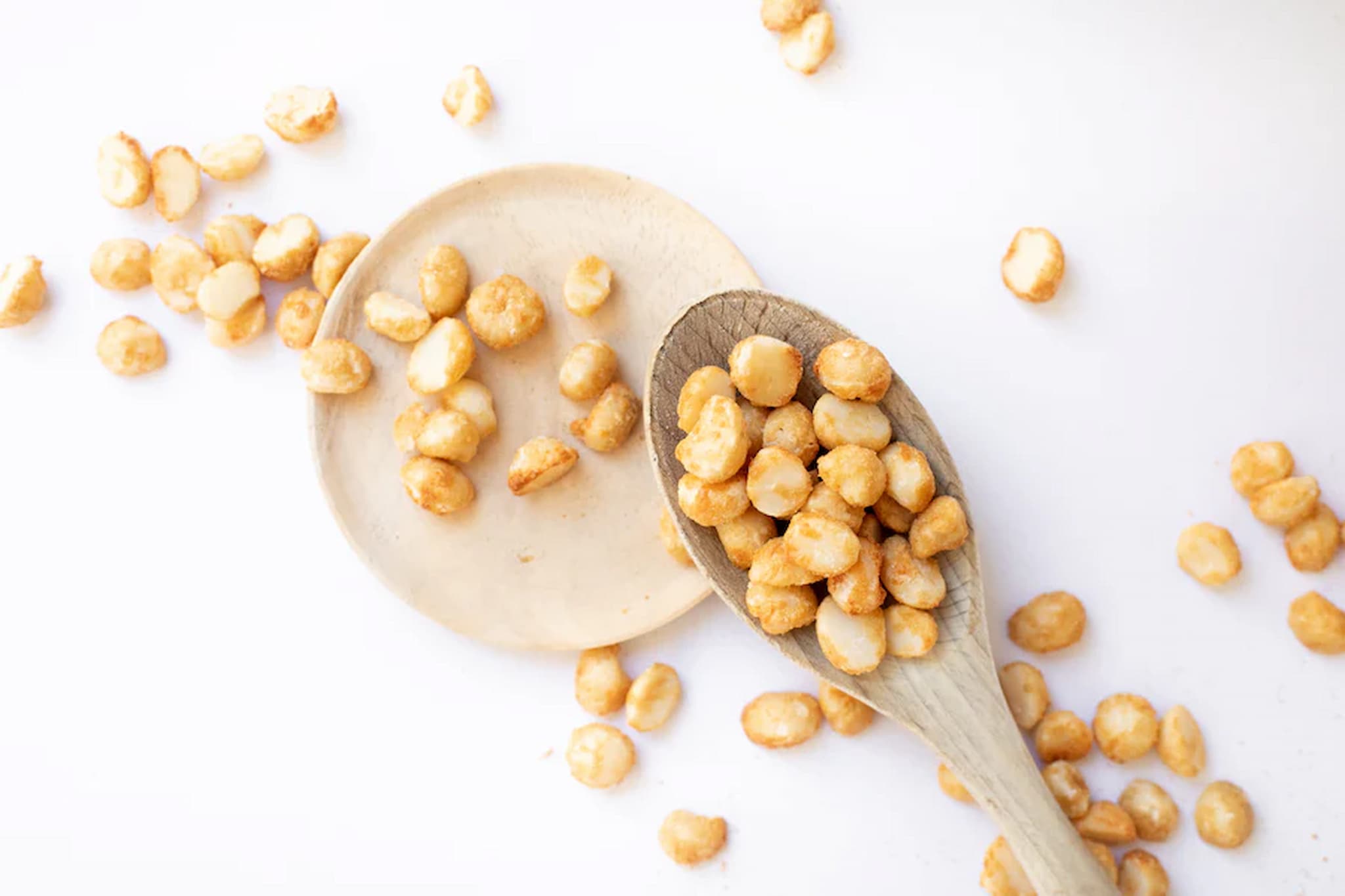 Crunchy hickory macadamias on wooden spoons on a white background photo from Nutworks.