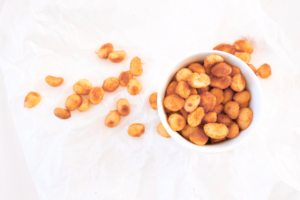 On a white surface, a portion of salted chili macadamias from Nutworks