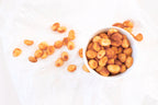 On a white surface, a portion of salted chili macadamias from Nutworks