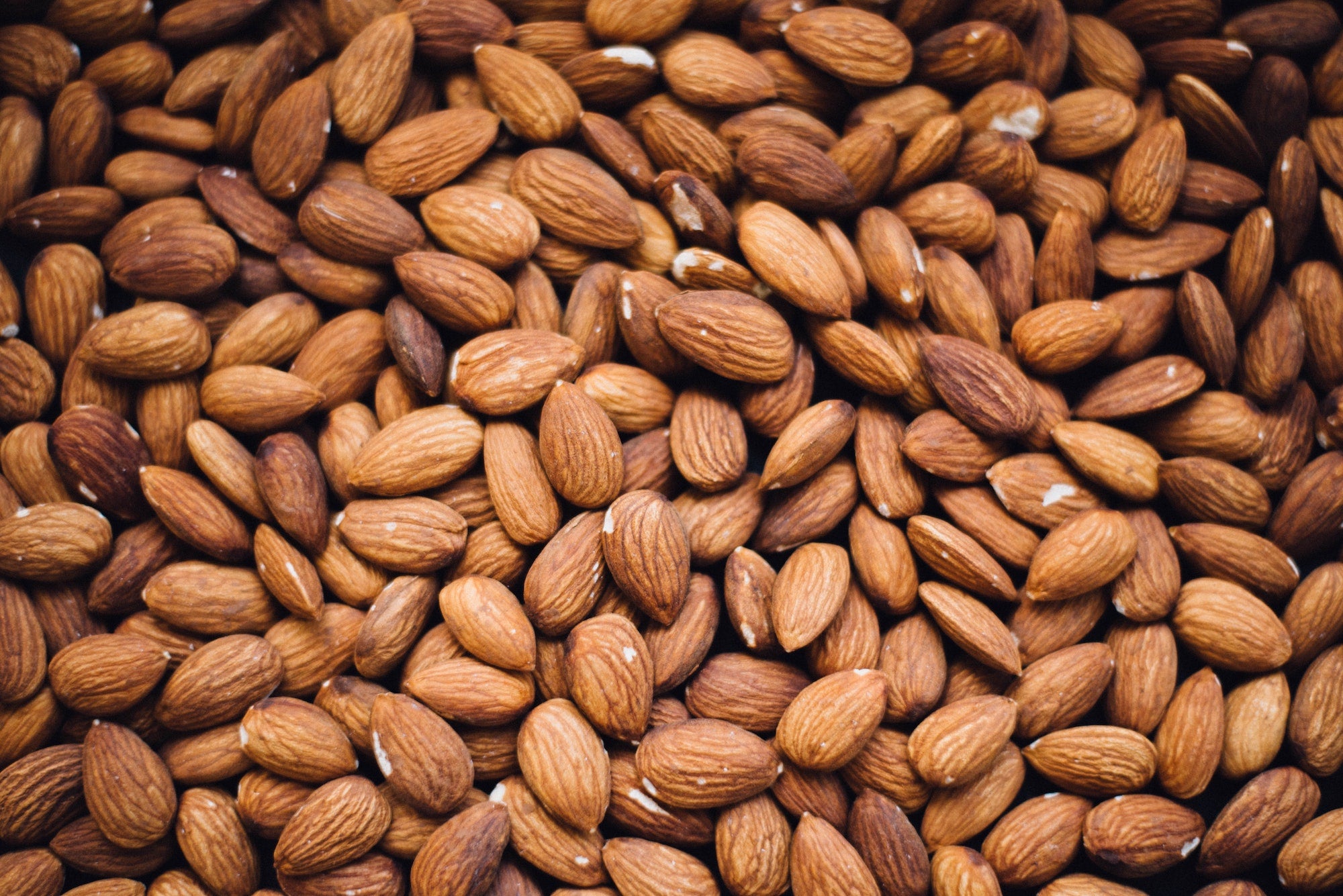 A close-up image of raw almonds without their skins, displaying a brown colour photo from Nutworks.